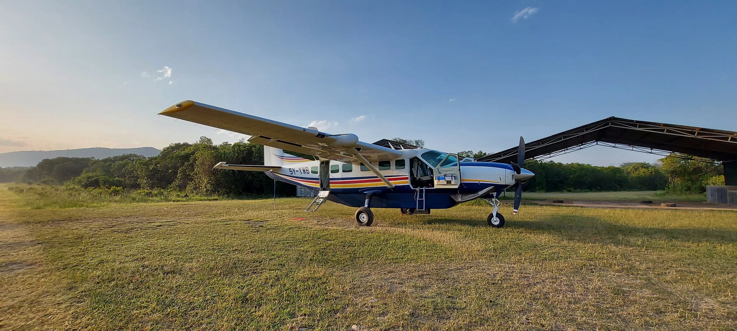 A Yellow Wings Grand Caravan parked on a lodge airstrip.