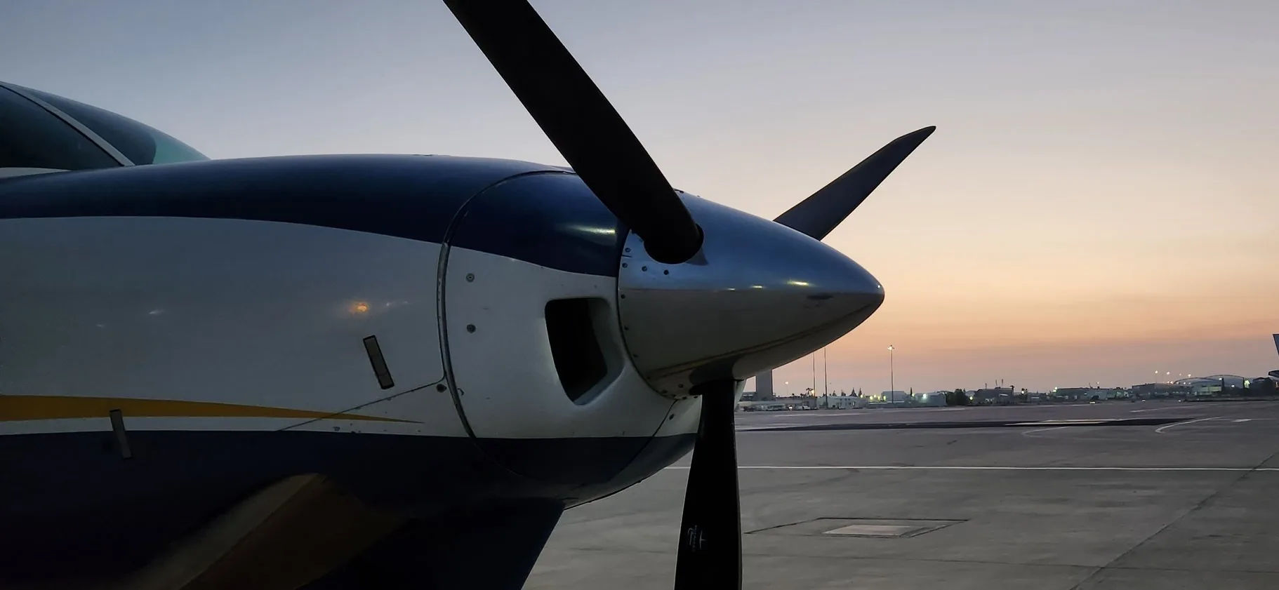 A Caravan's nose and four-blade propeller at sunset