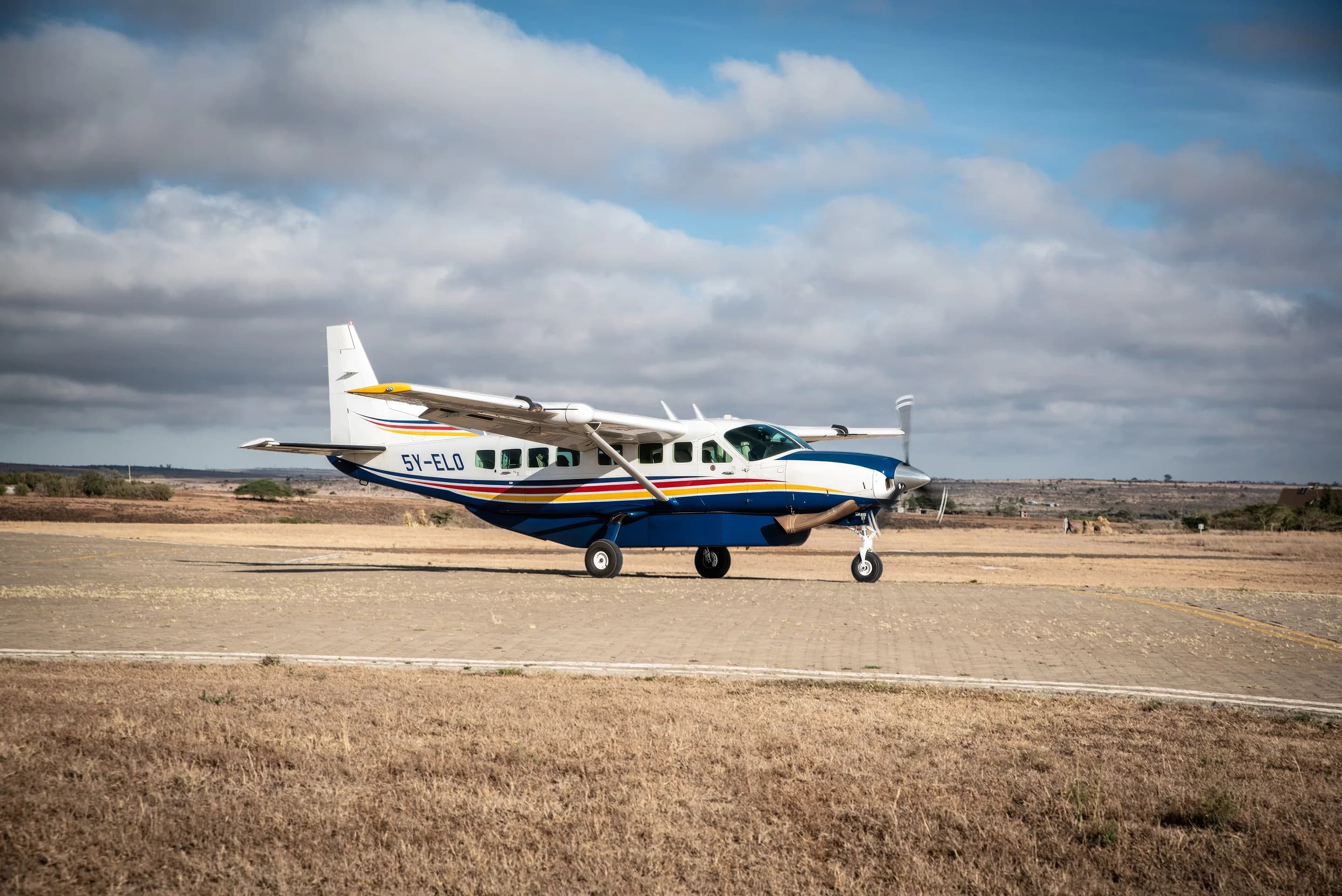 Yellow Wings Grand Caravan 5Y-ELO taxiing on a paved apron under a cloudy sky