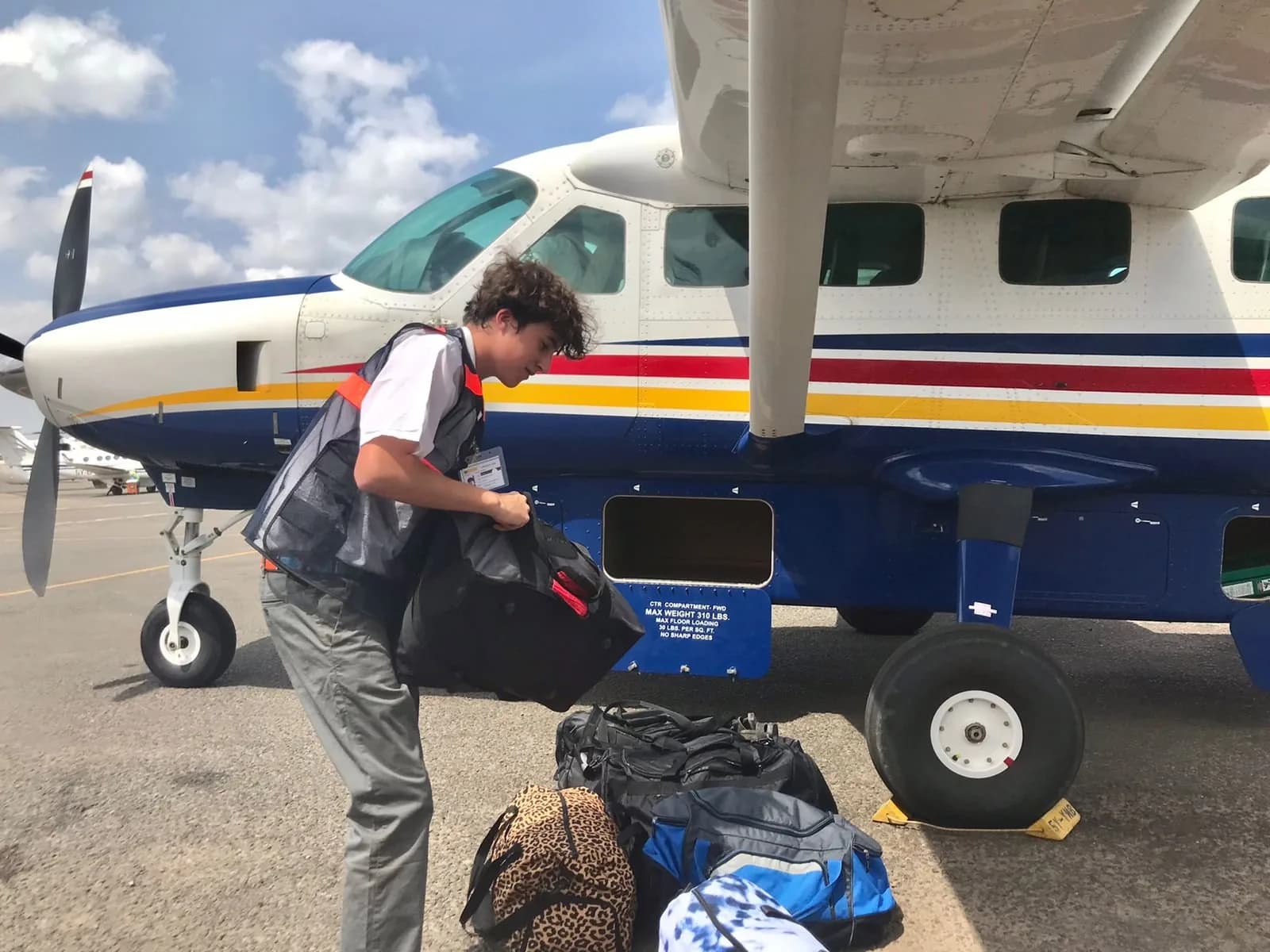 Ground crew loading bags into the cargo pod of a Yellow Wings Caravan
