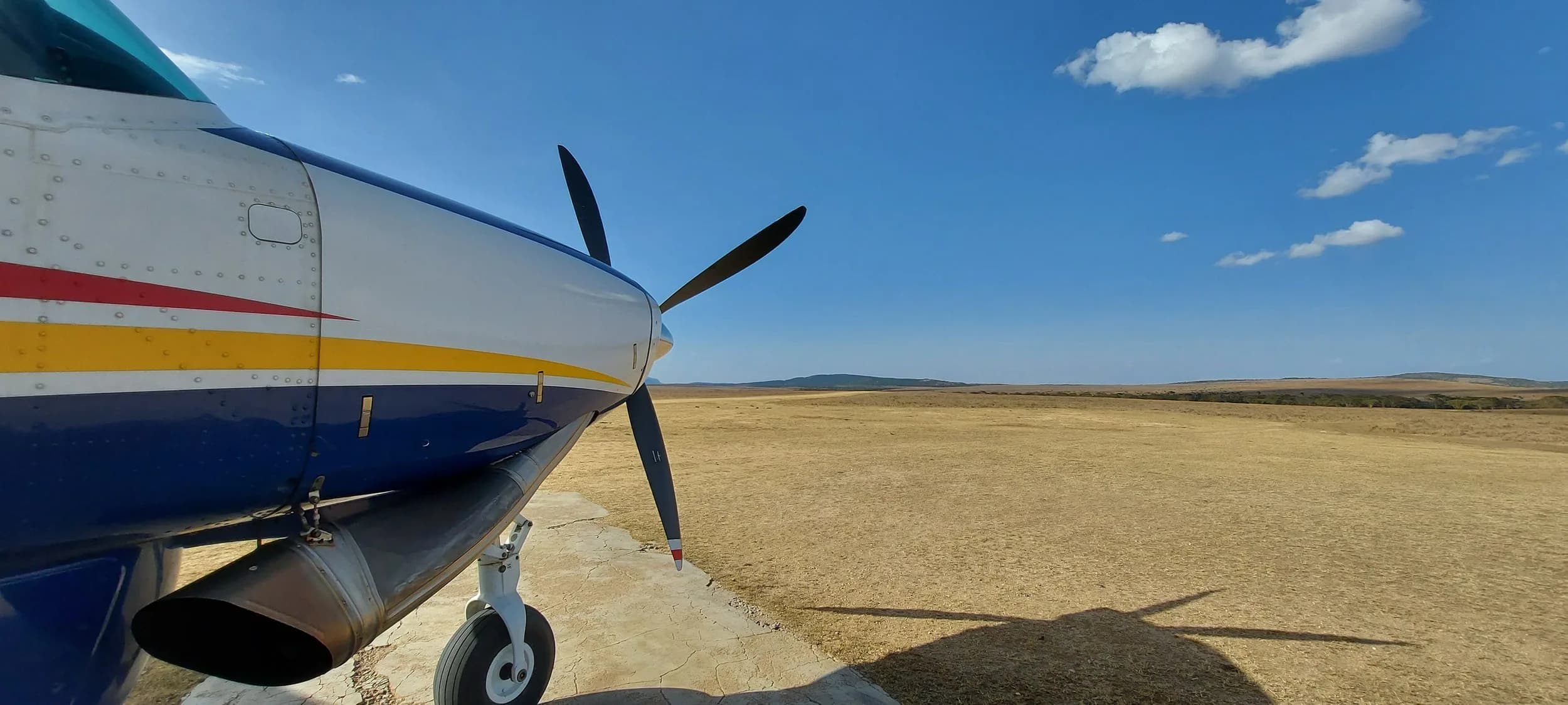 The nose and propeller of a Yellow Wings Caravan over dry plains