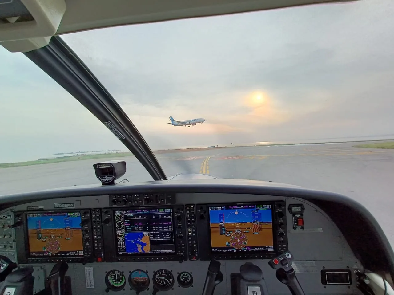 Taxiing at Entebbe from the flight deck, an airliner taking off ahead