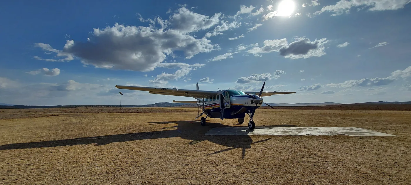 A Yellow Wings Caravan alone on a grass strip under a big sky